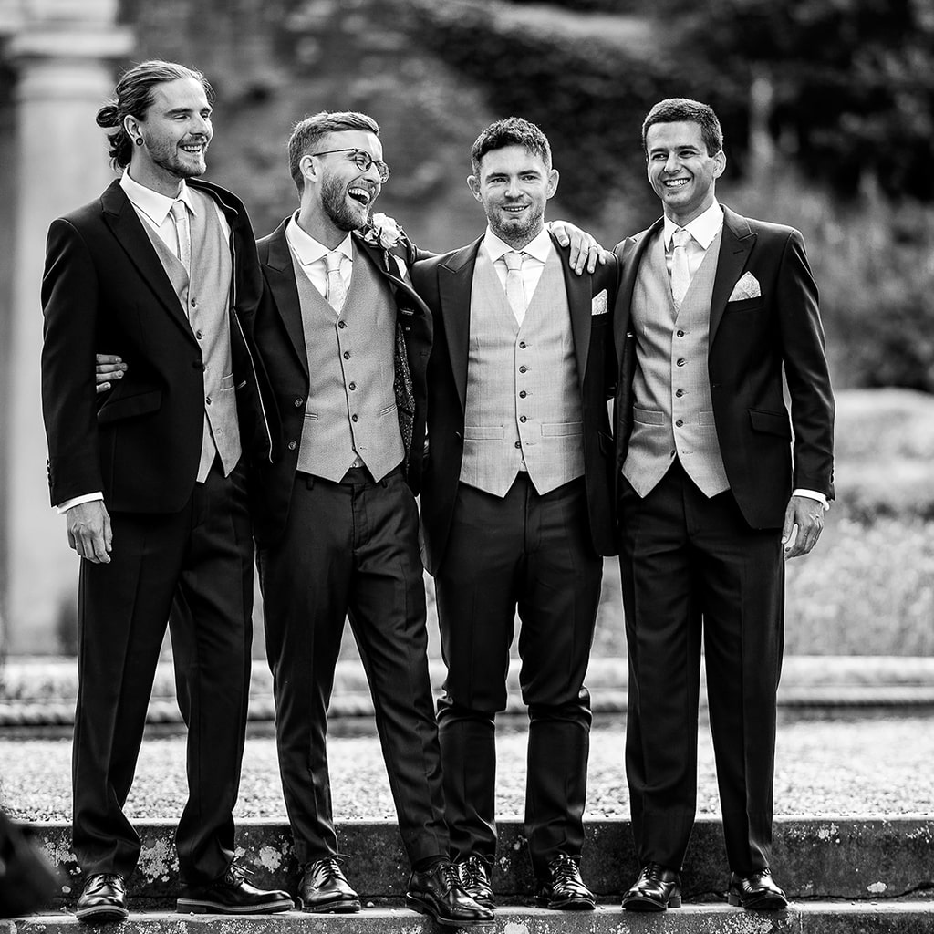 Black and white photo of Groomsmen standing on steps in WOTTON HOUSE garden